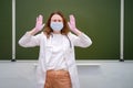 A worried school doctor in a medical mask in a classroom