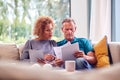 Worried Senior Couple Sitting On Sofa At Home Reviewing Personal Finances On Laptop Royalty Free Stock Photo