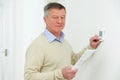 Worried Senior Man With Bill Turning Down Heating Thermostat Royalty Free Stock Photo