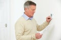 Worried Senior Man With Bill Turning Down Heating Thermostat Royalty Free Stock Photo