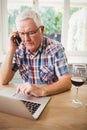 Worried senior man taking on phone while using laptop Royalty Free Stock Photo