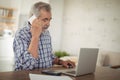 Worried senior man taking on phone while using laptop Royalty Free Stock Photo