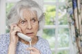 Worried Senior Woman Answering Telephone At Home