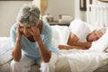 Worried Senior Woman Sits On Bed Whilst Husband Sleeps Royalty Free Stock Photo