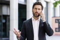 Worried and serious male businessman in suit and speaking expressively on the phone, solving problems and questions Royalty Free Stock Photo