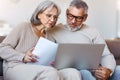 Worried serious senior family couple paying bills online on laptop while sitting on sofa at home Royalty Free Stock Photo