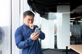 A worried and serious young Asian man is in the lobby of an office, hospital, bank with phone Royalty Free Stock Photo