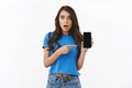 Worried and shocked, startled young woman say something hideous online, showing smartphone screen with disturbed