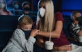 Worried small boy with mother in the cinema while watching film, coronavirus concept.