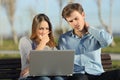 Worried students or entrepreneurs watching a laptop outdoors