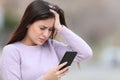 Worried teen checking bad news on smart phone