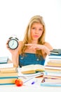 Worried teen girl pointing on alarm clock