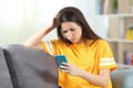 Worried teen reading bad news in a smart phone