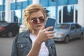 Worried teenager girl looking at her smart phone in a park with an unfocused background