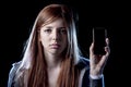 Worried teenager holding mobile phone as internet cyber bullying stalked victim abused Royalty Free Stock Photo