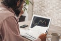 Worried and thoughtful man study stock exchange crypto charts on paper and computer display. Concept of economy and money Royalty Free Stock Photo