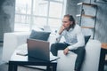 Worried and tired look. Overworked young businessman sitting on couch and watching at laptop Royalty Free Stock Photo