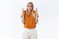 Worried, unsure timid cute blond girl in t-shirt, pants, fingers crossed, biting lip and frowning anxiously awaiting Royalty Free Stock Photo