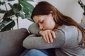 Worried upset Caucasian female suffering depression feeling lonely, alone at home. Depressed sad young woman sitting on couch in Royalty Free Stock Photo