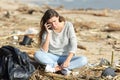 Worried volunteer cleaning a beach calling on phone