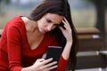 Worried woman on a bench checking phone Royalty Free Stock Photo