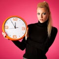 Worried woman with big orange clock gesturing delay, rush, nervous, stress because of lack of time.