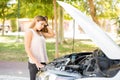 Worried woman with broken car on road