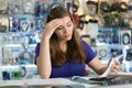 Worried Woman Checking Bills And Invoices In Computer Shop