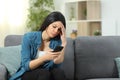 Worried woman checking smart phone content at home