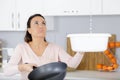 worried woman holding bucket while water droplets leak from ceiling Royalty Free Stock Photo