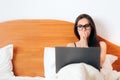 Worried Woman Looking at Laptop Sitting in Bed