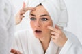 Worried woman looking at pimple on face