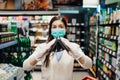 Worried woman with mask groceries shopping in supermarket looking at empty wallet.Not enough money to buy food.Covid-19 quarantine Royalty Free Stock Photo