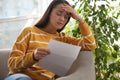 Worried woman reading letter on sofa at home Royalty Free Stock Photo