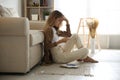 Worried woman reading letter while sitting on floor near sofa Royalty Free Stock Photo