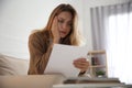 Worried woman reading letter on sofa at home Royalty Free Stock Photo