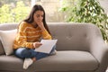 Worried woman reading letter on sofa at home Royalty Free Stock Photo