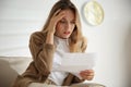 Worried woman reading letter on sofa Royalty Free Stock Photo