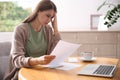 Worried woman reading letter at table in room Royalty Free Stock Photo