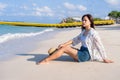 Worried woman sitting on beach with a straw hat on her knees tropical beach by the sea in sunny day time. Lonely girl sitting Royalty Free Stock Photo