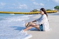 Worried woman sitting on beach with a straw hat on her knees tropical beach by the sea in sunny day time. Lonely girl sitting Royalty Free Stock Photo