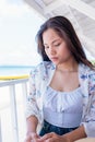 Worried woman sitting in the restaurant near the seaside with a tropical beach by the sea on a sunny day time. Lonely girl sitting Royalty Free Stock Photo