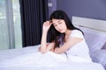 Worried woman thinking on bed in bedroom