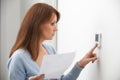 Worried Woman Turning Down Central Heating Thermostat Royalty Free Stock Photo