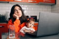 Worried Woman Working a Laptop Holding Her Baby Royalty Free Stock Photo