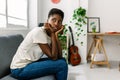 Worried young african woman sitting alone on sofa thinking about problems Royalty Free Stock Photo