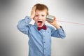 Worried young boy is listening with tin can telephone Royalty Free Stock Photo