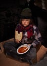 Worried young homeless boy eating charity food