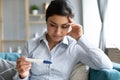 Worried young infertile indian woman holding pregnancy test