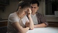 Worried young man lookign at his crying stressed wife crying on kitchen at night